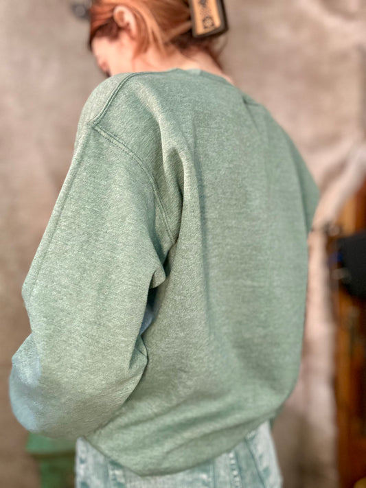 Back view of a green ranch style boot stitch sweater from Basil & Burch, featuring a relaxed fit