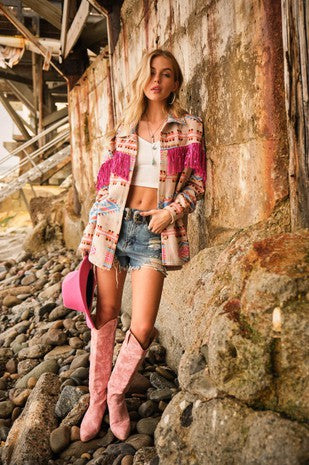Fashionable woman in Boho western outerwear with vibrant colors and fringes, styled with denim shorts