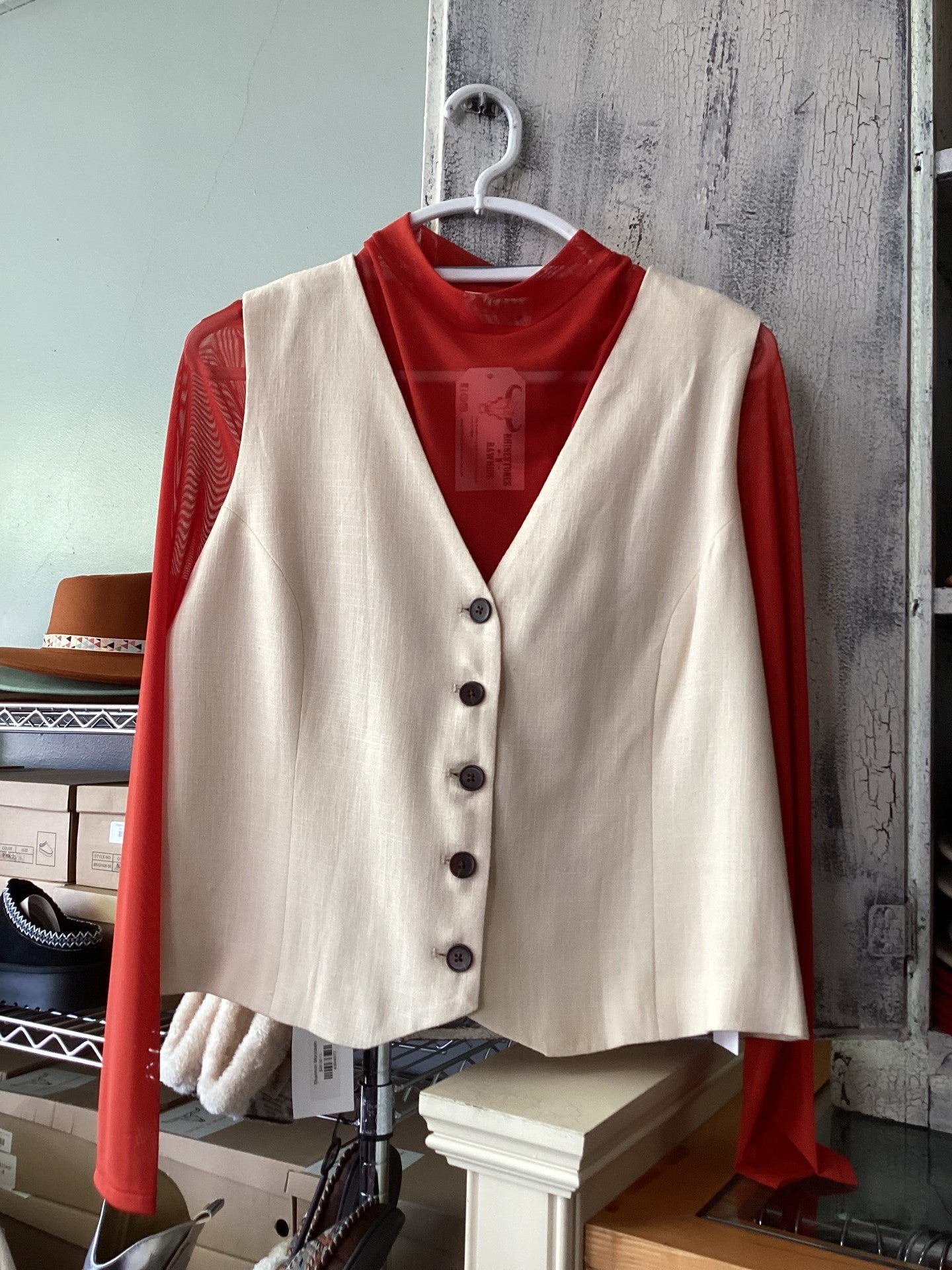 Cream button vest women displayed on a hanger with a red long-sleeve top underneath