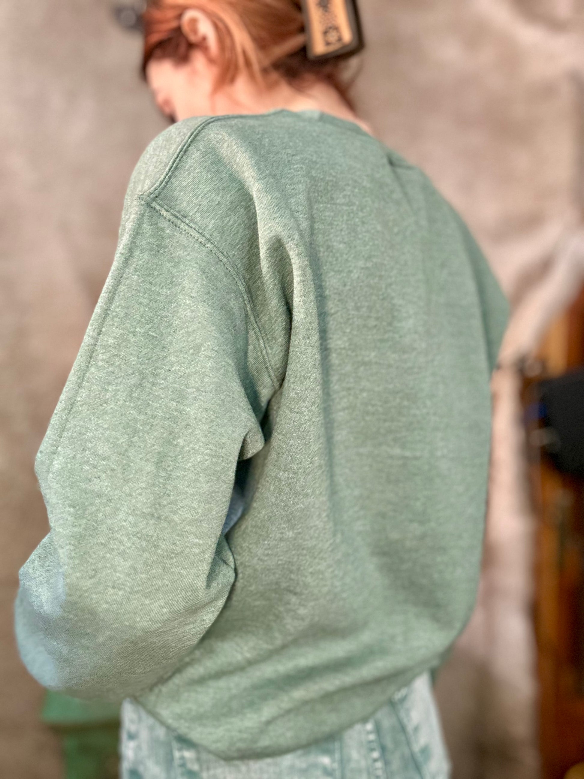 Back view of a green ranch style boot stitch sweater from Basil & Burch, featuring a relaxed fit