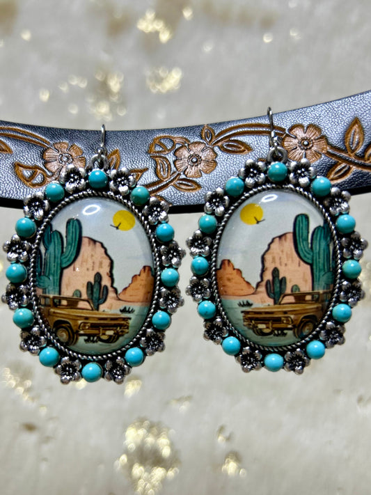 Western style jewelry earrings featuring a desert landscape with cacti and vintage cars in vibrant colors